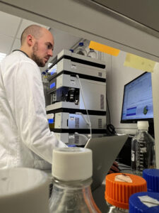 Man in lab coat looking at data on a PC